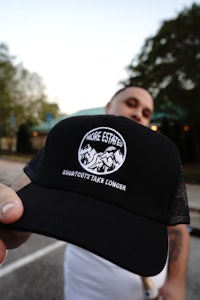a man holding up a black trucker hat