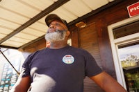 a man with a beard standing outside of a restaurant